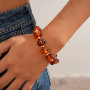 Close-up of amber acrylic beaded bracelet with gold spacers on a model's wrist