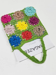 Detail of colorful hand-crocheted floral tote bag with green stitch pattern and yarn texture