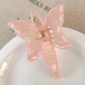 Detail of pink butterfly hair claw clip with ribbon weaving on translucent plastic