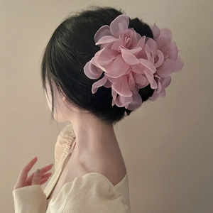 Detailed view of a pink organza flower hair claw clip with delicate layered petals on a model