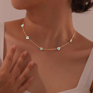 Fashionable gold necklace with heart-shaped evil eye pendants worn by a female model