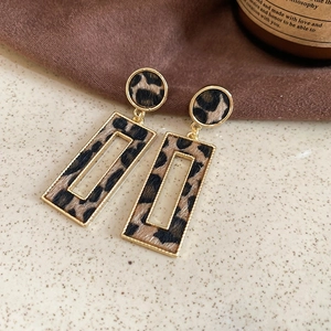 Macro shot of gold-framed leopard print geometric earrings with hollow rectangle design