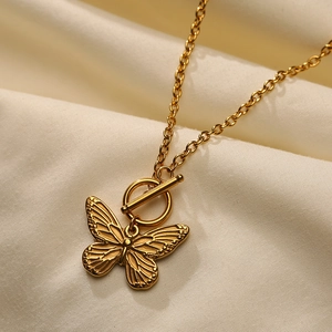 Close-up of golden butterfly necklace with T-bar toggle clasp on silk background