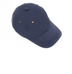 Detail of navy blue cotton baseball cap featuring gold ventilation eyelets and curved brim
