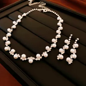 Elegant pearl and rhinestone choker jewelry set with matching drop earrings on black display
