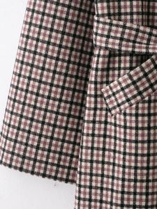 Close-up of pink and black plaid wool fabric texture and matching belt detail on coat