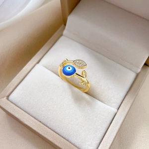 Gold leaf ring with blue evil eye zircon and micro-set diamonds on beige velvet