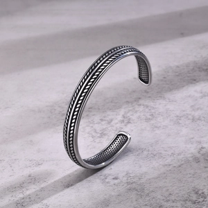 Macro detail of men's vintage silver open bangle with braided rope texture design