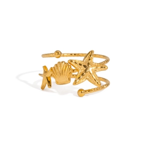 Détail macro d'étoile de mer dorée et de coquillages sur une bague en acier inoxydable