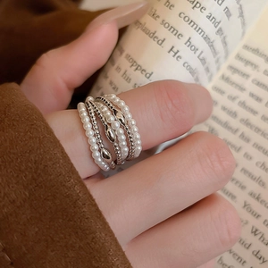 Close-up of stacked multi-layer pearl rings and silver beaded bands for women