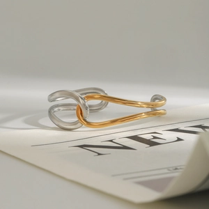Detail of minimalist mixed-metal knot open bangle in gold and silver finish
