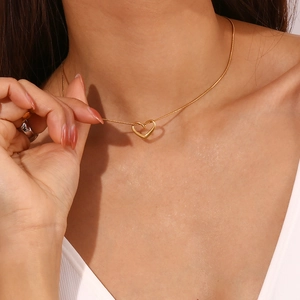 Close-up of a 18K gold plated heart pendant on a thin snake chain worn by a model