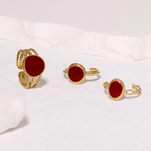 Detailed shot of three gold rings with deep red enamel inlay on a white stone base
