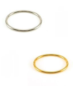 Detail of minimalist gold and silver stainless steel oval bangles with a polished finish