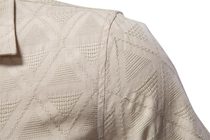 Macro shot of khaki cotton shirt collar showing geometric jacquard weave texture