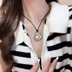Detail of silver liquid heart pendant necklace on a black cord worn by a model