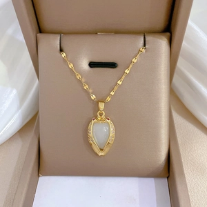 Détail du pendentif ailes dorées avec jade coeur et rubis sur tissu de soie blanche