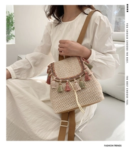 Detail of straw backpack with colorful tassels and adjustable straps on a model