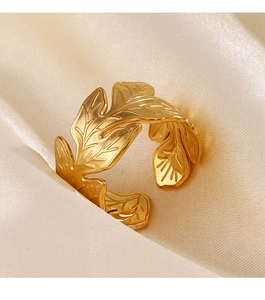 Macro shot of gold leaf-shaped ring with detailed vein textures on white silk