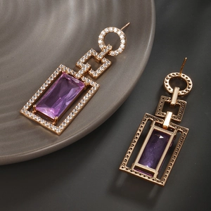 Détail de boucles d'oreilles dorées vintage avec grandes pierres de zircon violet