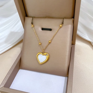 Detail of gold heart pendant with shell inlay and small zircon on a beaded chain