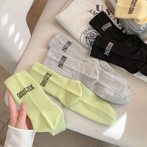 Detail view of cotton crew socks in pastel colors with knitted text and ribbed cuffs