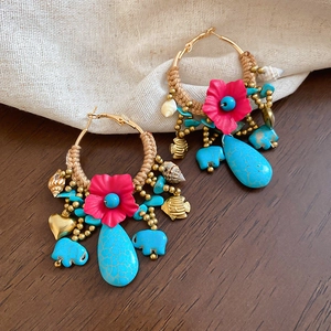 Detail of ethnic hoop earrings with turquoise elephant charms and woven floral accents