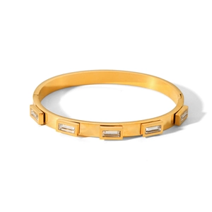 Macro detail of gold stainless steel bangle featuring five rectangular zircon stone inlays