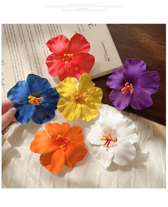 Close-up of vibrant six-color fabric frangipani hair clips on a wooden tabletop