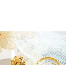 Detailed close-up of golden wavy and smooth rings on delicate white lace fabric