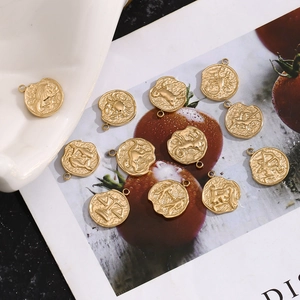Macro shot of 14K gold plated zodiac pendants with detailed relief patterns on ceramic