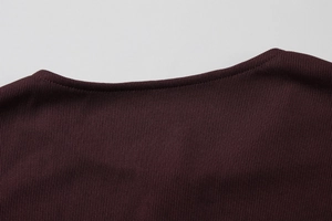 Gros plan sur l'encolure en tricot côtelé bordeaux et les détails de couture soignés