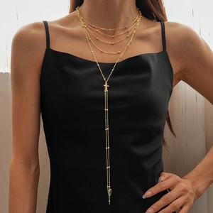 Golden multi-layer chain necklace with small beads and cross pendant on a model