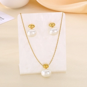 Elegant gold chain necklace and matching pearl earrings set on white textured display