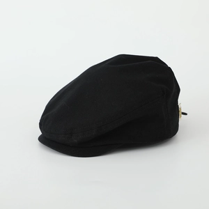 Detailed side view of black cotton beret cap featuring a small yellow brand label