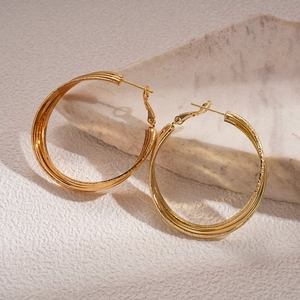 Detailed close-up of 18k gold plated multi-layer geometric hoop earrings on stone base
