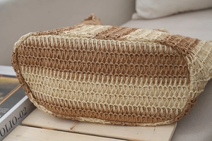 Close-up detail of the woven texture and bottom structure of this striped straw tote bag