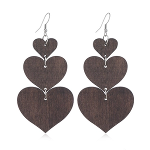 Macro shot of retro dark brown three-layer wooden heart earrings on white background