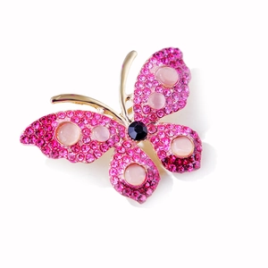 Detailed view of butterfly brooch with rose pink rhinestones and opal-like gems on gold metal