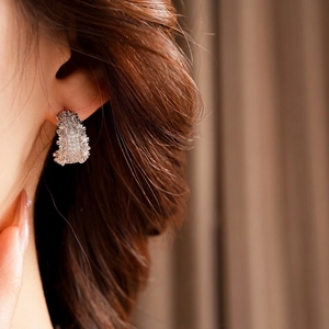 Boucles d'oreilles C dorées élégantes avec zircons étincelants portées par un mannequin