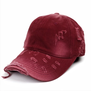 Close-up of distressed vintage burgundy baseball cap with ripped details and worn fabric
