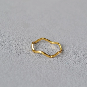 Detailed view of a minimalist gold wave ring with a polished metallic finish on a grey surface