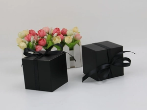 Close-up of black square gift boxes featuring elegant silk ribbon bows on white background