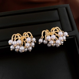 Close-up of vintage gold tassel earrings with white pearls on a black textured tray