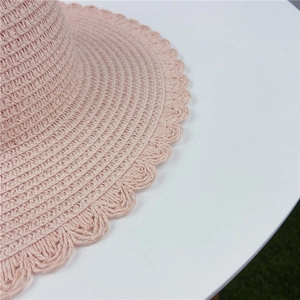 Gros plan détaillé d'un chapeau de paille rose avec un bord ondulé festonné élégant.