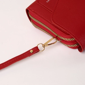 Detail view of red leather crossbody wallet featuring dual gold zippers and wrist strap