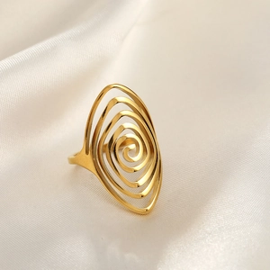 Detailed view of a gold spiral vortex ring on a luxury white silk fabric background