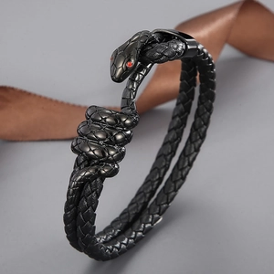 Detail of black woven leather strap and metal snake head with red gemstone eyes