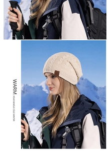 Detail view of the thick cable knit texture and leather patch on a beige winter hat