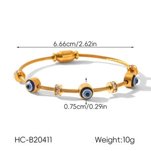 Detail of 18k gold cable bracelet with evil eye beads and crystal charms on white background